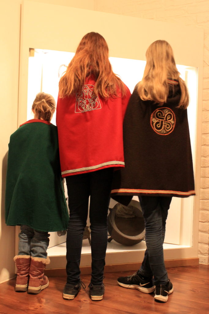 Trois enfants de dos portant des capes inspiration Viking. Dans la partie pour les enfants du Musée National à Copenhague.